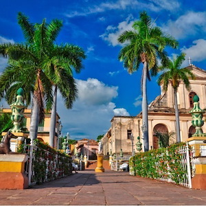 View of a cathedral in Dominican Republic with a blue sky in the background and palm trees