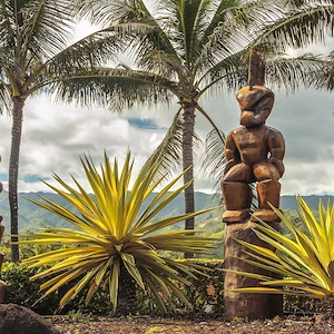 Three Polynesian tiki statues in a tropical background. Oahu, Hawaii